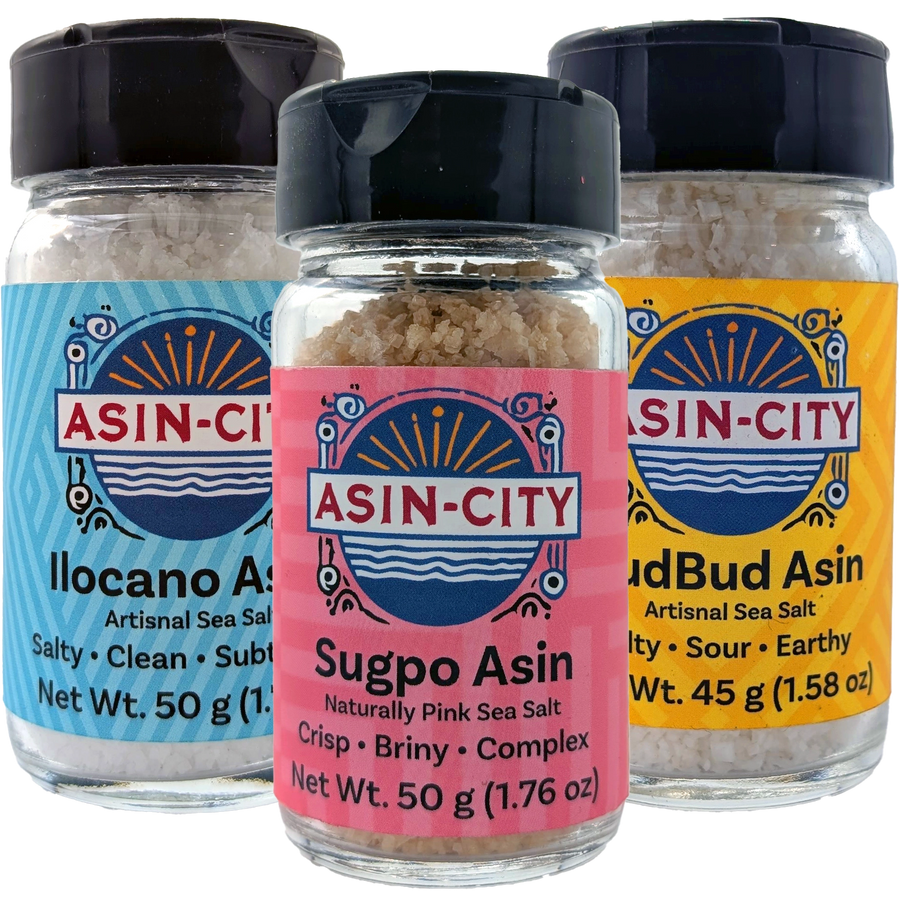 Three jars of Asin-City sea salt with colorful labels on a white background