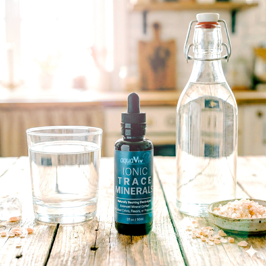 Bottle of aquaViv Ionic Trace Minerals on a wooden table with a glass of water and a jar of salt.